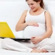 Mulher grávida deitada na cama navegando na internet