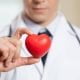 Médico com estetoscópio vermelho nos ombros segurando um coração de plástico